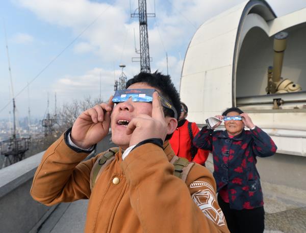游客用赠送的太阳观测眼镜观赏日偏食